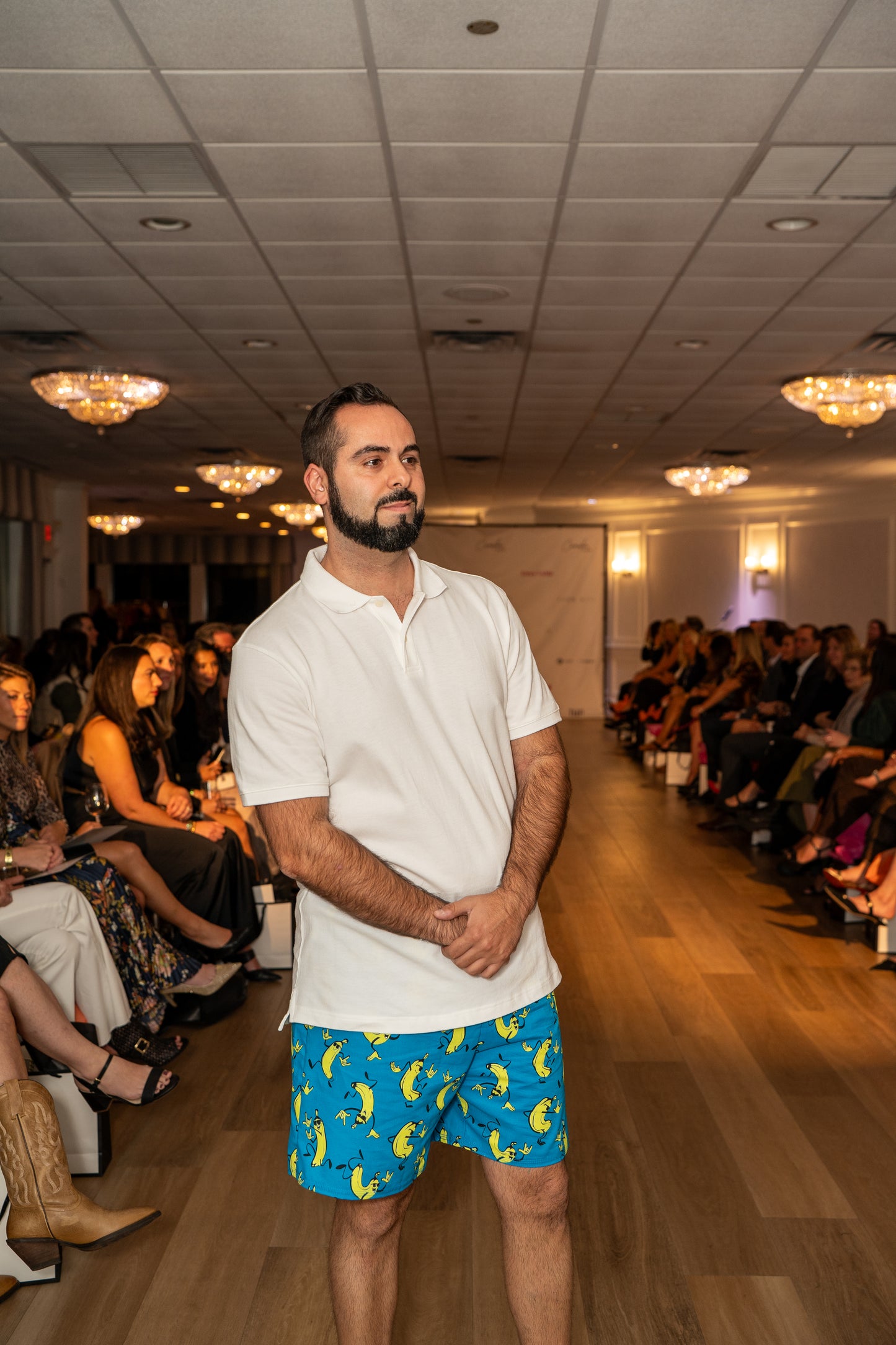 Man on a runway wearing a white polo shirt and blue shorts with banana pattern